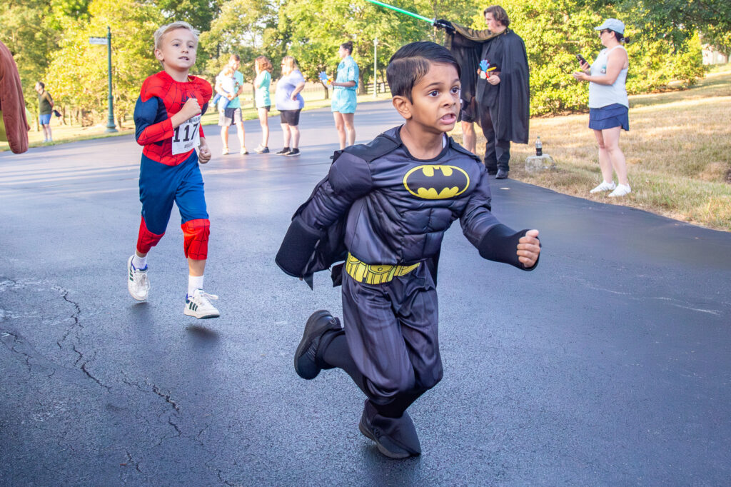 A young boy dressed as Batman running in the race.
